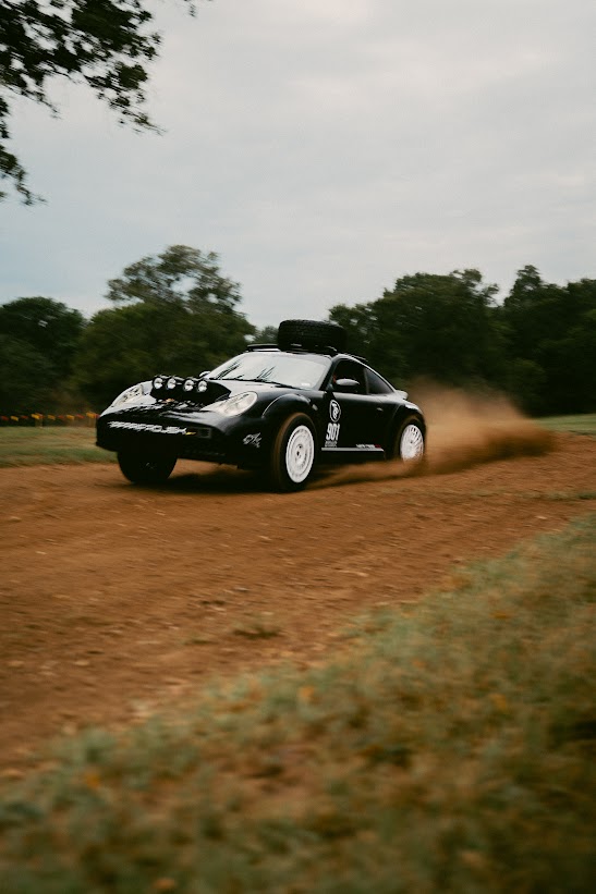 Black 911 Heritage RX driving a dirt course with dust behind it